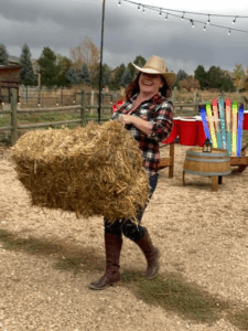 Sara Lawrason, Senior Program Director at Operation Altitude, moving a hay bale to set the scene for a corporate retreat with western ski-style vibes. Photo courtesy of Operation Altitude.