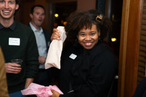 Smiling guest holding a wrapped gift during a holiday event in Boulder, surrounded by other attendees enjoying the celebration.