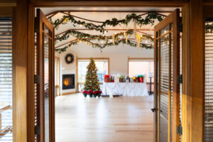 Holiday event setup at Rembrandt Yard in Boulder with a decorated Christmas tree, gift table, and greenery hanging from wooden beams.